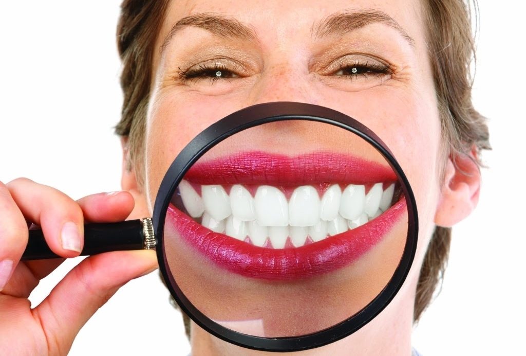 Beautiful young woman teeth and magnifying glass